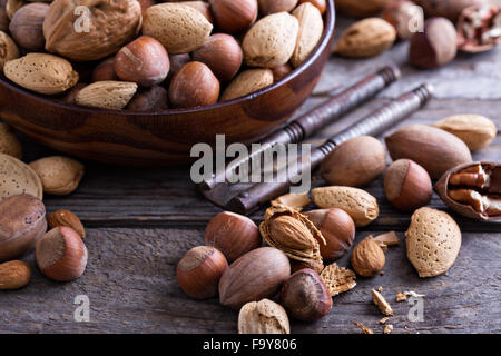 Varietà di noci con guscio in una ciotola marrone Foto Stock