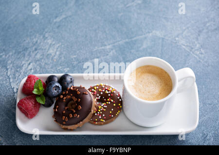 Vetri di piccole dimensioni mini ciambelle e caffè in una tazza di espresso Foto Stock