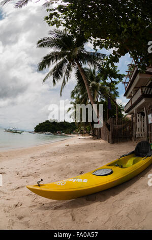 Kayak giallo recante sulla spiaggia di sabbia con Palm tree Foto Stock