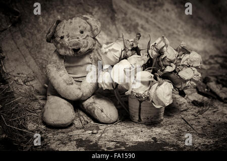 Vintage orsacchiotto con sbiadito Rose in un grungy impostazione Foto Stock