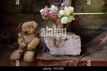 Vintage orsacchiotto con sbiadito Rose in un grungy impostazione Foto Stock