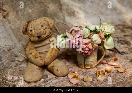 Vintage orsacchiotto con sbiadito Rose in un grungy impostazione Foto Stock