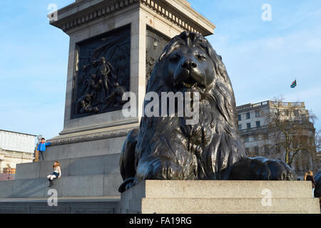 LONDON, Regno Unito - 19 dicembre: Dettaglio di uno dei quattro statue di leoni che circondano di Nelson's colonna in Trafalgar Square con childr Foto Stock