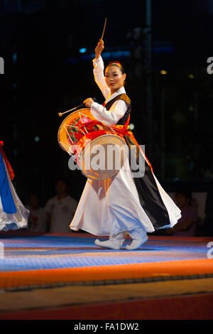 Tradizionalmente un vestito in coreano hanbok donna sul palco a suonare janggu tradizionali tamburi in corrispondenza di un libero estate mostra nei pressi del municipio Foto Stock