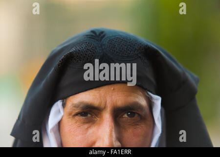 Metà faccia ritratto del Kashmir donna musulmana che indossa tirata indietro niqab nero pieno viso velo esponendo il suo viso e gli occhi Foto Stock