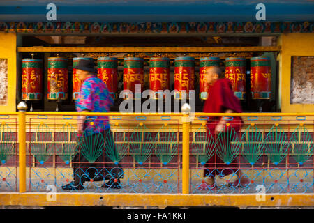 I buddisti in motion blur rosso di filatura ruote della preghiera intorno alla casa del Tibet Dalai Lama, un punto di pellegrinaggio Foto Stock