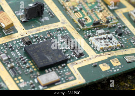 Una pila di pezzi rotti di telefoni cellulari e batterie del telefono su un muschi e licheni coperto rock Foto Stock