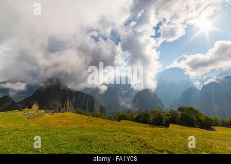 Machu Picchu illuminata dalla luce del sole di mattina. Ampio angolo di vista dalle terrazze sopra nella retroilluminazione con scenic sky. Foto Stock