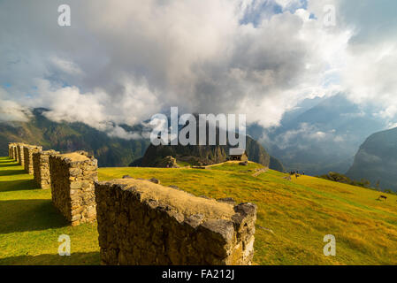 Vista insolita di Machu Picchu illuminata dalla luce del sole di mattina che esce dall'apertura nuvole. L'Inca city è il più vis Foto Stock