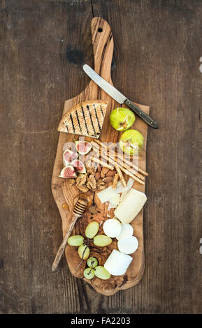 Vino antipasti set: selezione di formaggi, miele, uva, mandorle, noci, grissini, figure in legno d'ulivo serve scheda sopra la ruggine Foto Stock