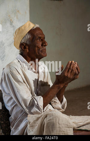 Profilo di Indian maschio bianco da indossare a mendicare con le sue mani a tazza fuori chiedendo per il cambiamento all'ingresso di una moschea Foto Stock