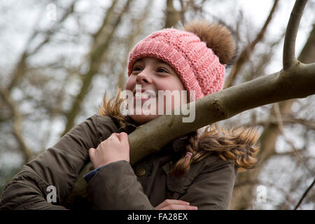 10 enne ragazza seduta su un albero Foto Stock