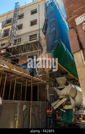 Lavoratore in esecuzione una costruzione di gru di sollevamento è un contenitore di cemento nella città vecchia di Barcellona, in Catalogna, Spagna Foto Stock