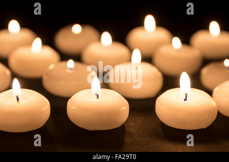 Gruppo di candele accese in uno sfondo nero Foto Stock