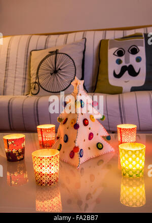 L'Italia, Chtistmas atmosfera in casa elegante. Piccole candele sul tavolo e un albero di Natale fatto ​​of panno. Foto Stock