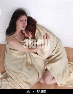Due ragazze tenere su ogni altro per comfort, avvolto in una coperta. Per i superstiti di un disastro, Storm, uragano o terremoto Foto Stock
