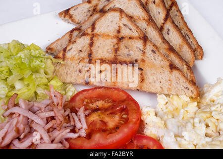 Prima colazione inglese tradizionale con uova strapazzate, pomodori, patate, toast e insalata fresca Foto Stock