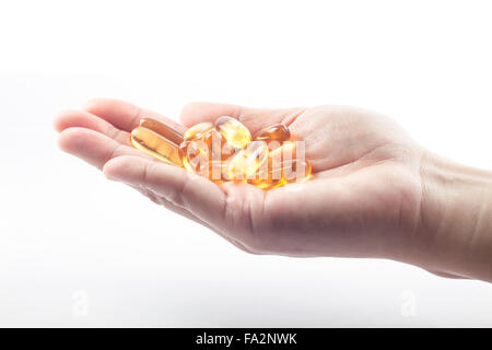 Mano che trattiene l'olio di pesce capsule su sfondo bianco, stock photo Foto Stock