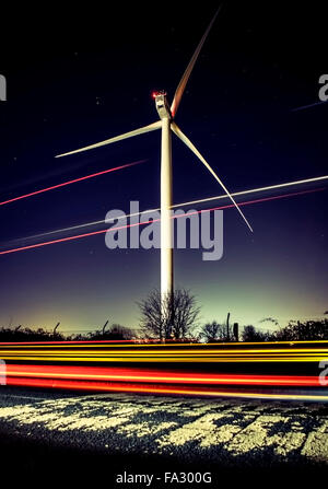 Turbina eolica durante la notte con cielo stellato e sentieri di luce Foto Stock