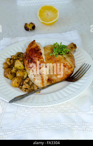 Una porzione di pollo arrosto servita con castagne e funghi in una piastra bianca Foto Stock