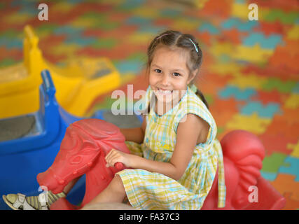 Bambina sul cavallo a dondolo. Foto Stock