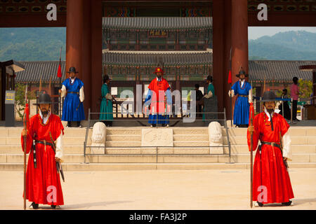I soldati in rosso, blu antichi abiti tradizionali armi di contenimento proteggendo l'ingresso motivi di Gyeongbokgung Palace a Seul Foto Stock