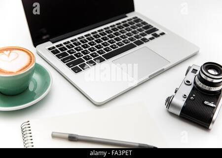 Portatile, fotocamera vintage, tazza di caffè, blocco note e penna isolate su sfondo bianco Foto Stock