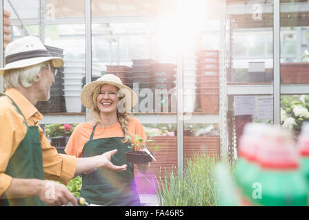 Giardiniere dando pianta a shop assistant, Augsburg, Baviera, Germania Foto Stock