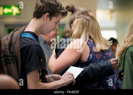 Un ragazzo adolescente apre la sua a livello di risultati busta mentre una ragazza celebra con il suo insegnante a Abbeywood Community School, Regno Unito Foto Stock