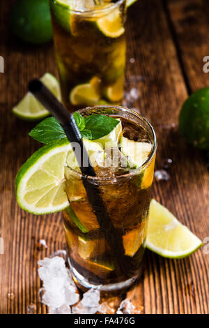 Longdrink freddo (Cuba Libre) marrone con il rum e lime fresco rustico sfondo di legno Foto Stock