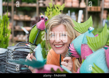 Ritratto di donna shop assistant che mostra fake uccelli in serra, Augsburg, Baviera, Germania Foto Stock