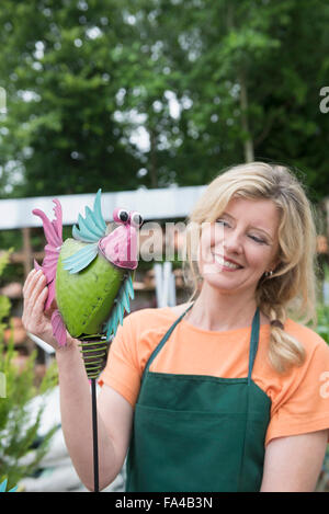 Femmina assistente shop mostra fake bird in serra, Augsburg, Baviera, Germania Foto Stock