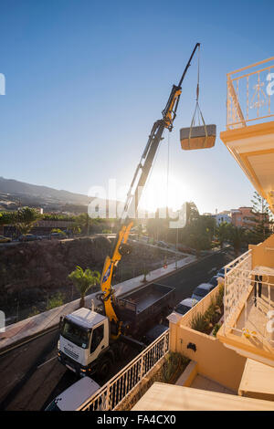 Montata su camion gru di sollevamento di una vasca calda dall'ultimo piano di un palazzo di appartamenti, Playa San Juan, Tenerife, Isole Canarie, Spa Foto Stock