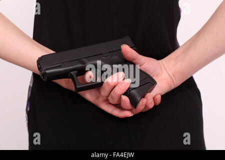 Giovane donna con una pistola dietro la schiena Foto Stock