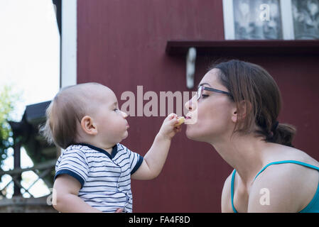 Baby boy alimentazione di sua madre a prato, Monaco di Baviera, Germania Foto Stock