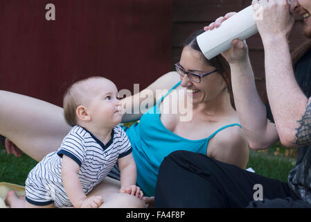 Baby boy guardando al suo padre che sta guardando attraverso un rotolo di asciugamani di carta in prato, Monaco di Baviera, Germania Foto Stock