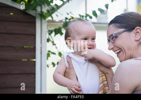 Metà donna adulta e suo figlio divertirsi in giardino e ridere, Monaco di Baviera, Germania Foto Stock