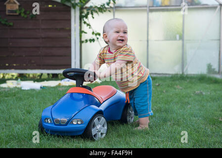Bambino con il suo giocattolo auto e pianto nel prato, Monaco di Baviera, Germania Foto Stock