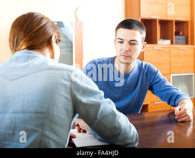 Uomo a rispondere alle domande del lavoratore di outreach con la carta in ufficio Foto Stock