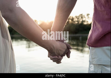 Metà vista in sezione di una coppia in amore tenendo le mani durante il tramonto, Baviera, Germania Foto Stock
