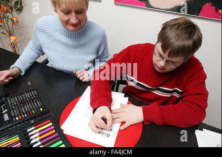 Genitore Single guardando suo Figlio di scrivere il suo nome su un pezzo di carta Foto Stock