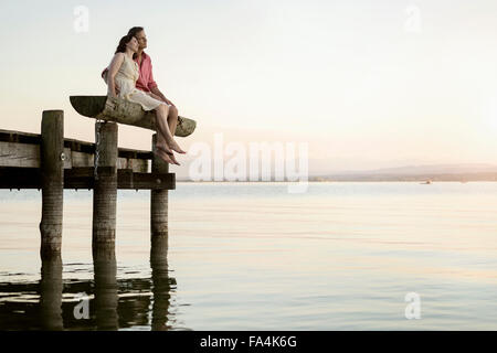 Coppia matura seduta sul molo che si affaccia su un lago, Baviera, Germania Foto Stock