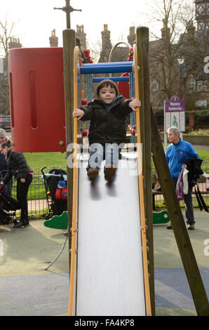 Un giovane ragazzo gioca su una diapositiva in un parco giochi. Foto Stock