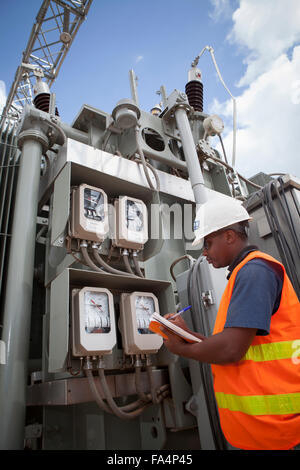 Un ingegnere elettrico gestisce apparecchiature a Mtoni stazione di servizio a Zanzibar, Tanzania Africa Orientale. Foto Stock