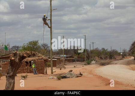 Stringa di lavoratori nuovi cavi di alimentazione in un villaggio rurale vicino a Dodoma, Tanzania Africa Orientale. Foto Stock