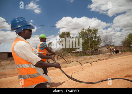 Stringa di lavoratori nuovi cavi di alimentazione in un villaggio rurale vicino a Dodoma, Tanzania Africa Orientale. Foto Stock