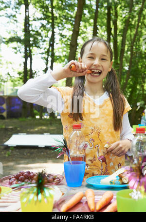 Ritratto di una ragazza di mangiare la carota nel parco, Monaco di Baviera, Germania Foto Stock