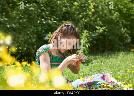 Ragazza rendendo corona floreale nel parco, Monaco di Baviera, Germania Foto Stock