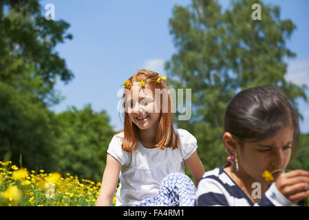 Ragazza rendendo corona floreale con il suo amico indossa corona floreale nel parco, Monaco di Baviera, Germania Foto Stock