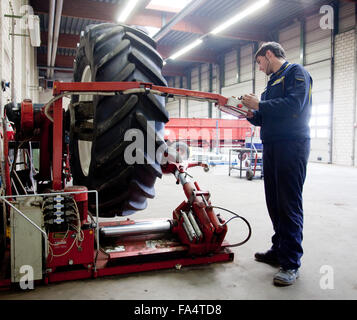 Apprendista montatore cambiare un pneumatico del trattore. Foto Stock